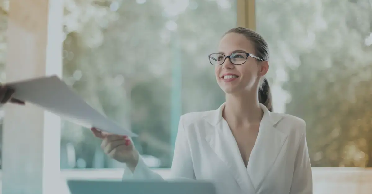 Woman in glasses with white shirt hands a piece of paper to someone, it's an accurate record to speed up claims