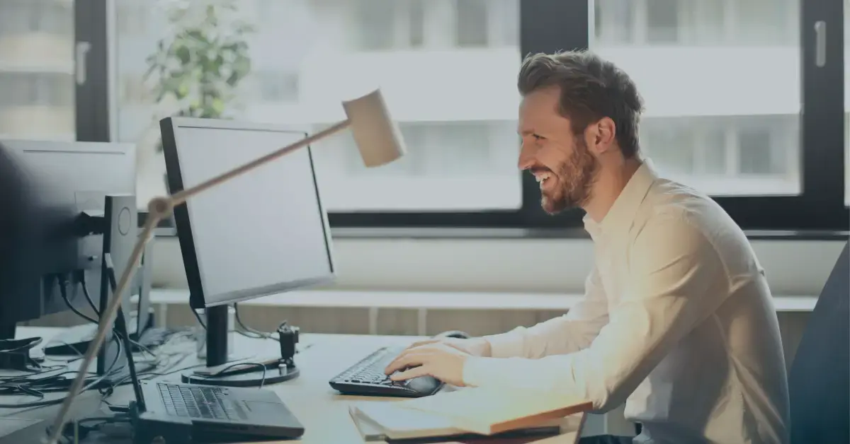 man happily working on computer with automation in insurance