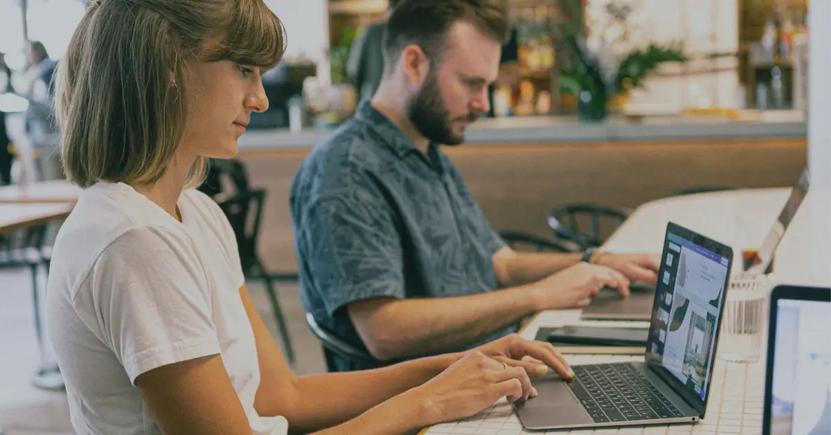 man and a woman sitting next to each other working on their laptops
