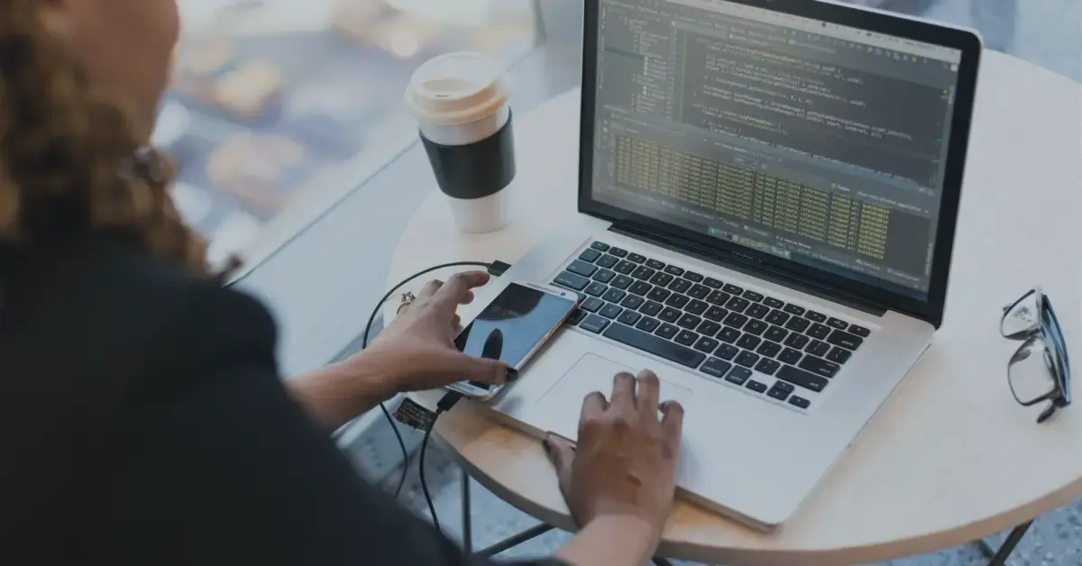 woman working on a laptop with her phone next to her