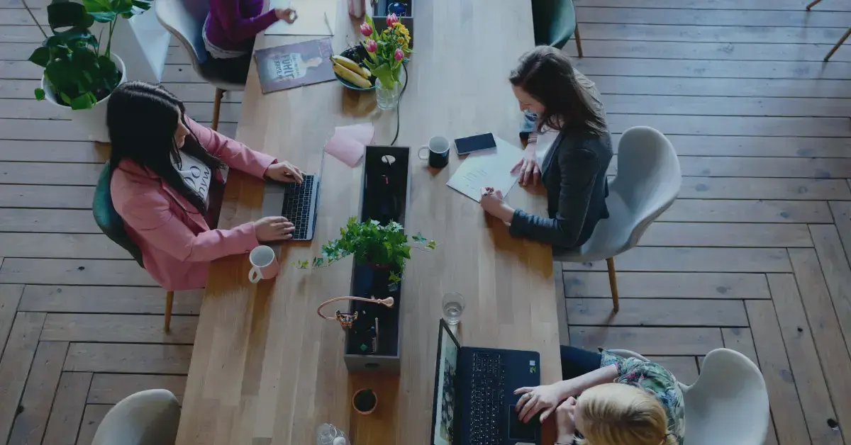 people working at a desk on laptops